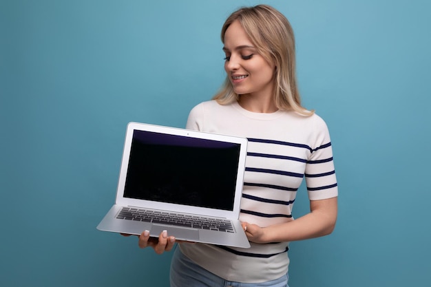 Concentrated girl student showing laptop screen with mockup on blue background