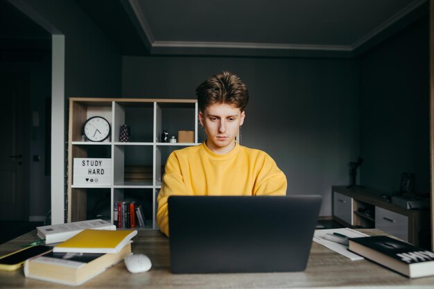 Concentrated handsome young man sitting at a table with books at home