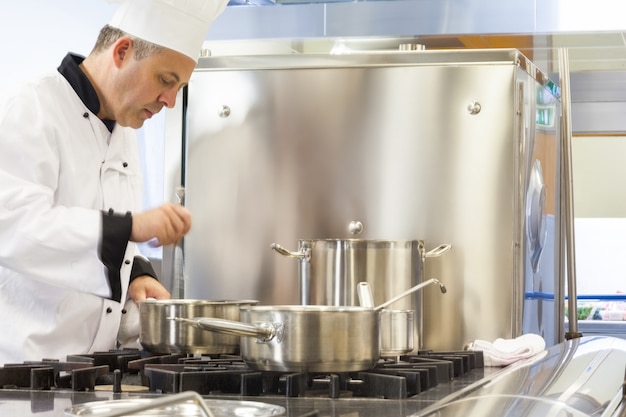 Concentrated head chef stirring in pot