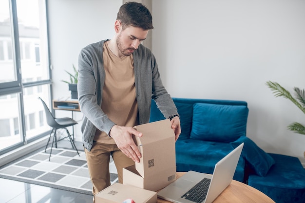 Concentrated Internet shop worker packing goods for shipping