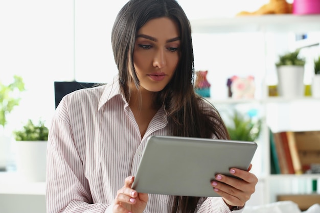 L'aspetto concentrato della signora nel lavoro sullo schermo del tablet da casa risolve in remoto l'attività di lavoro