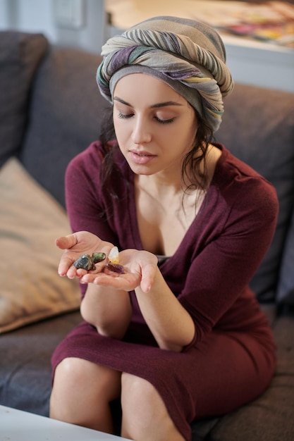 Concentrated lady looking at different healing crystals