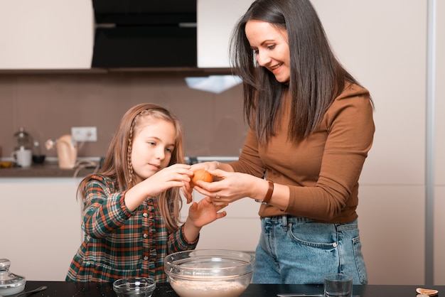 Concentrated little girl is helping her mother with cooking.