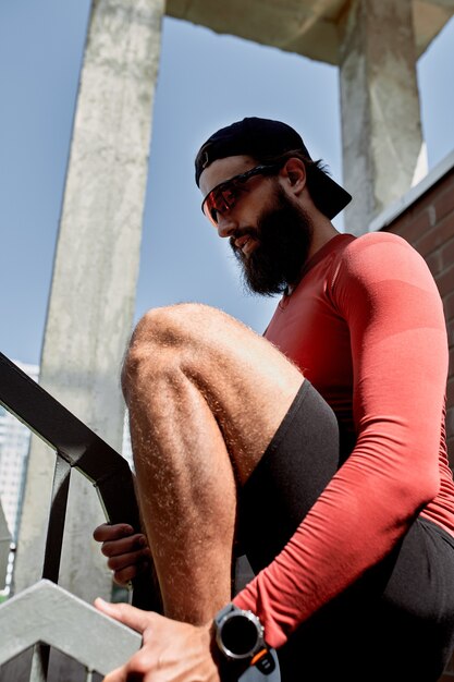 Concentrated male athlete running up stairs to make training\
more intensive. sporty handsome young man training alone outdoors.\
staircase workout concept.