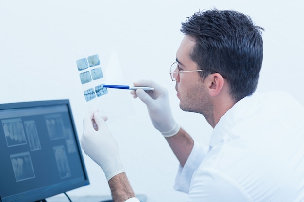 Concentrated male dentist looking at x-ray