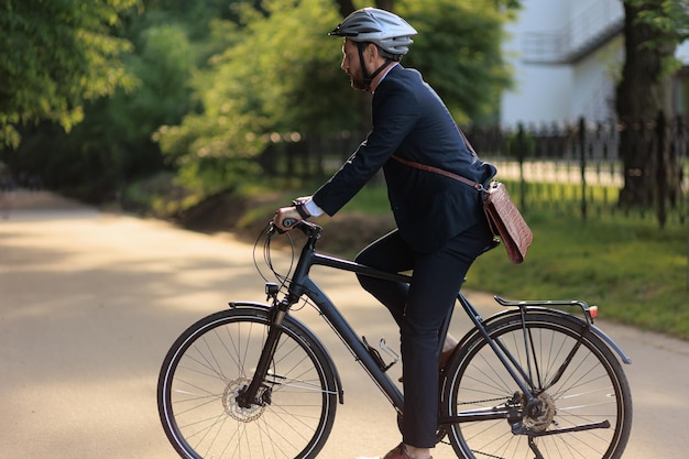 Фото Сосредоточенный работник-мужчина катается на велосипеде в городском парке