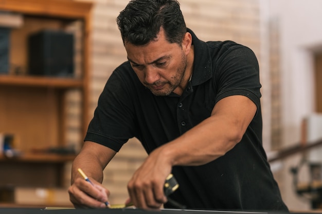 Photo concentrated man drawing on a surface using a meter in a workshop