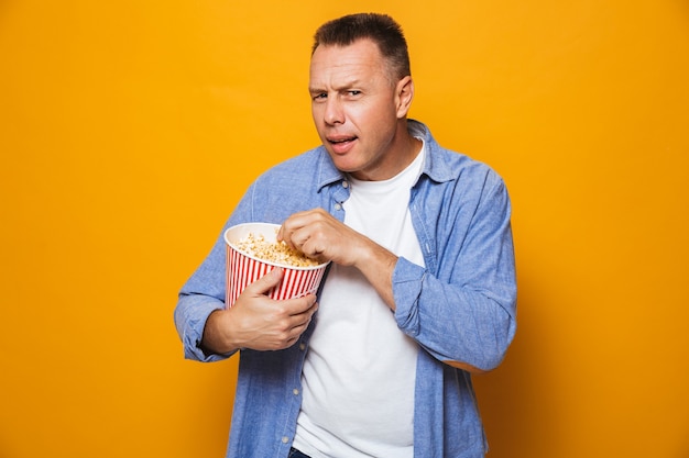 Photo concentrated man eating pop corn watch film looking.