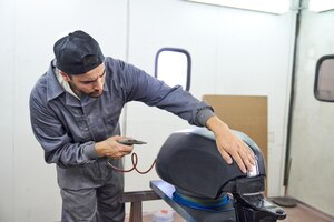Concentrated man painting motorbike fuel tank in garage