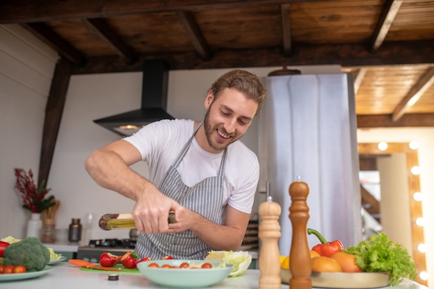 Un uomo concentrato che mette l'olio in un piatto