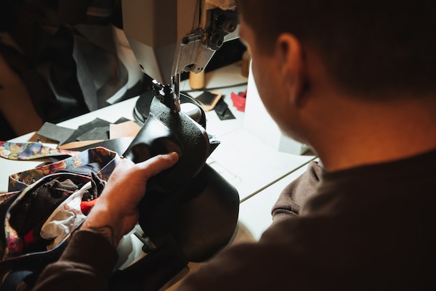 Concentrated man shoemaker at footwear workshop.