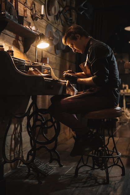 Concentrated man shoemaker at footwear workshop.