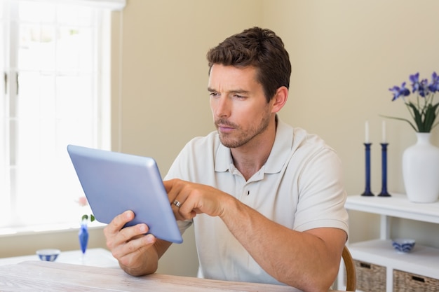 Concentrated man using digital tablet on table