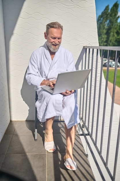 Uomo concentrato con il suo computer portatile seduto sul balcone