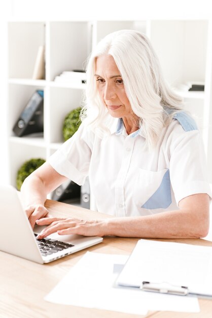 Concentrated mature woman sitting indoors working