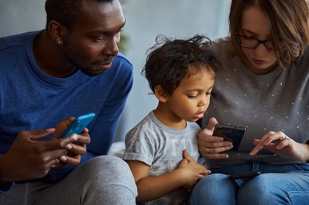 Concentrated members of family sit together on one sofa