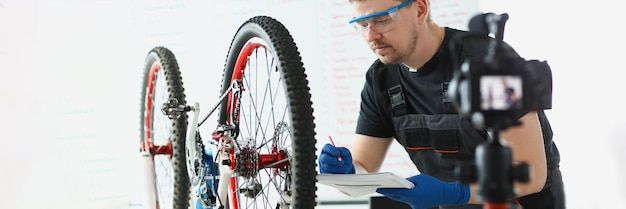 Concentrated middle aged mechanic writing down needed details to repair vehicle