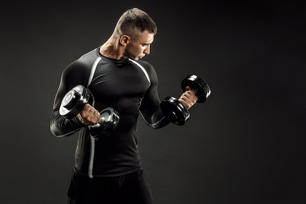 Concentrated muscular man doing exercise with dumbbell