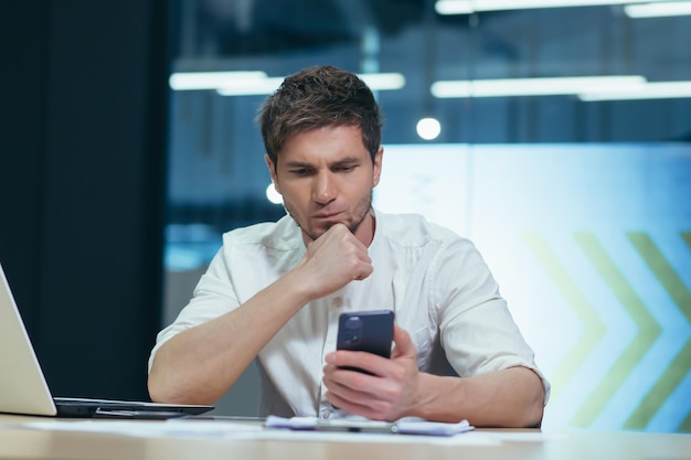 Concentrated and pensive businessman reads the news from the phone the man works in the office