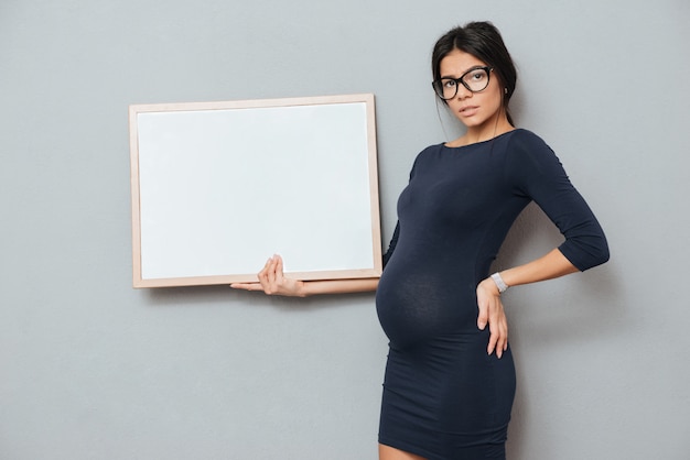 Concentrated pregnant businesswoman holding copyspace blank.