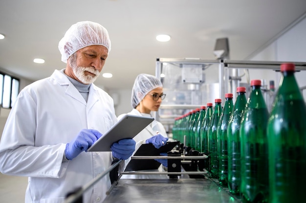 Concentrated quality control workers controlling production of bottled drinking water in factory