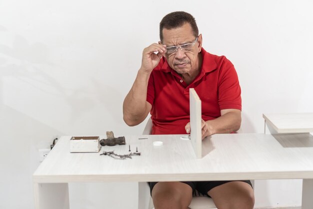 Foto concentrato uomo anziano con occhiali di sicurezza tavolo di assemblaggio