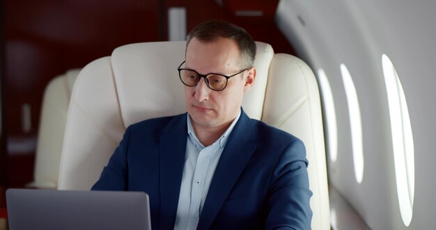 Concentrated serious businessman using laptop in first class