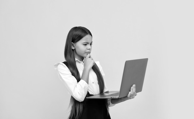 Concentrated serious teen girl in school uniform study on laptop knowledge