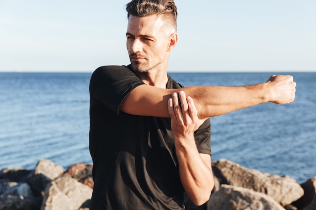 Concentrated sportsman doing stretching exercises