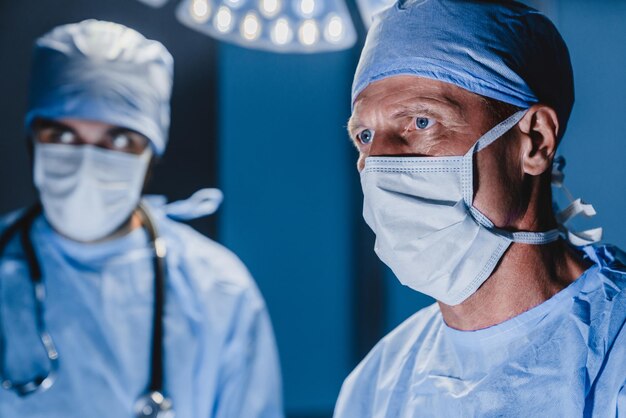 Photo concentrated surgeon performing surgery with his team in hospital operating room