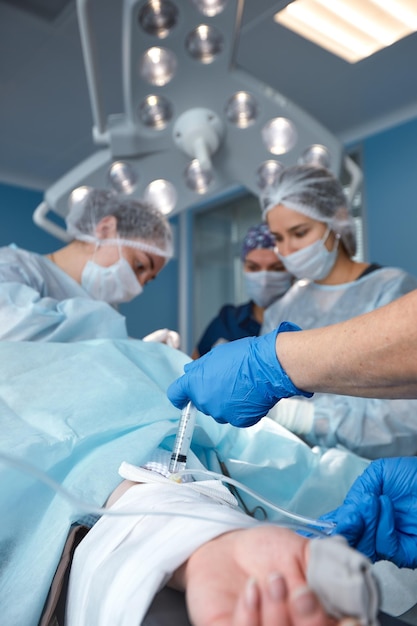 수술실에서 환자를 수술하는 집중 외과 팀 복잡한 기계로 수년간 교육을 받은 잘 훈련된 마취과 의사가 수술 내내 환자를 따릅니다.