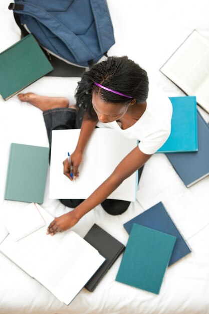 Concentrated teen girl studying sitting on her bed 