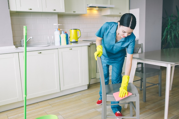 Concentrated woman bows down to chair and cleans it with rag