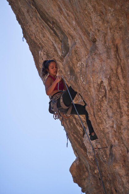 Concentrated woman climbing mountain using special\
equipment