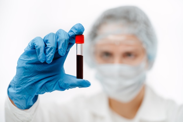 Сосредоточенная женщина-врач в резиновых перчатках держит стеклянную пробирку с анализом образца крови на коронавирус