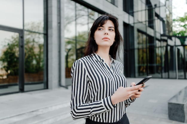 Donna concentrata che pensa con il telefono in mani