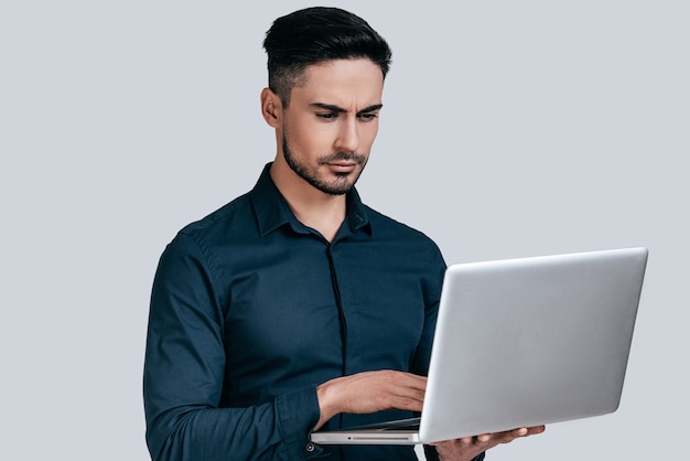 Concentrated at work.  Good looking young man in shirt working on laptop 