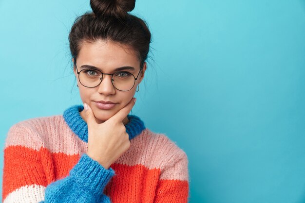 a concentrated young amazing woman posing isolated over blue wall.