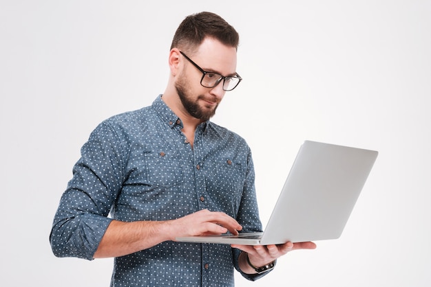 Foto giovane uomo barbuto concentrato che per mezzo del computer portatile