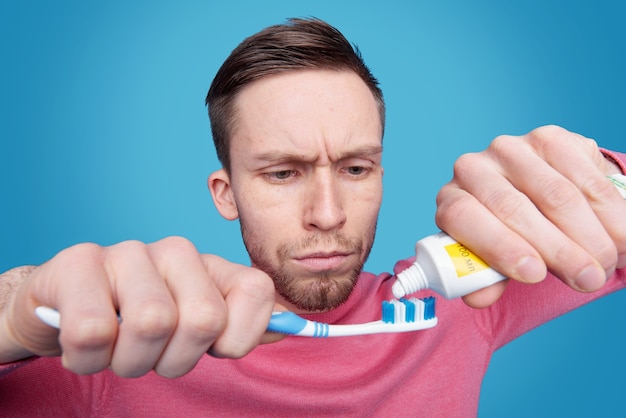 Concentrated young bearded man with frowning forehead preparing for brushing tooth