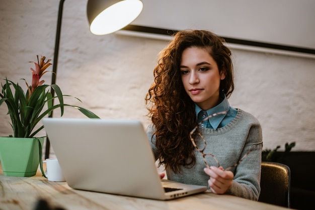 Concentrated young beautiful businesswoman working on laptop in bright modern office.