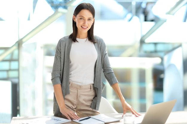 Concentrato giovane bella donna di affari che lavora al computer portatile in ufficio moderno luminoso