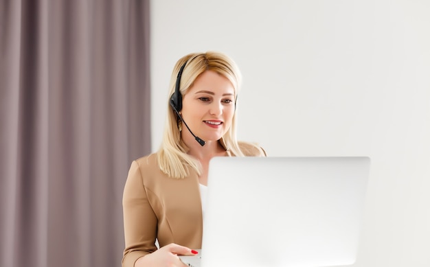 Concentrated young beautiful businesswoman working on laptop in bright modern office