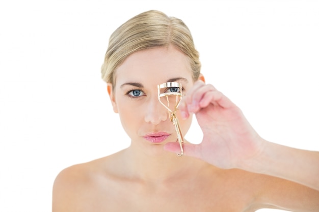 Concentrated young blonde woman using eyelash curler