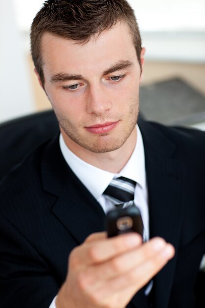 Concentrated young businessman sending a text 