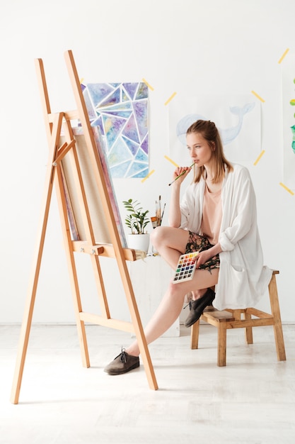 Concentrated young caucasian lady painter at workspace