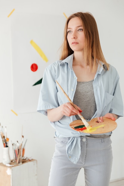 Concentrated young caucasian lady painter