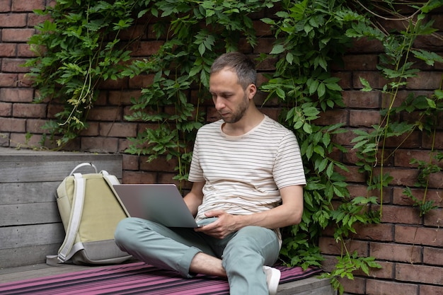 Concentrated young man freelance web developer working remotely at outdoor work environment