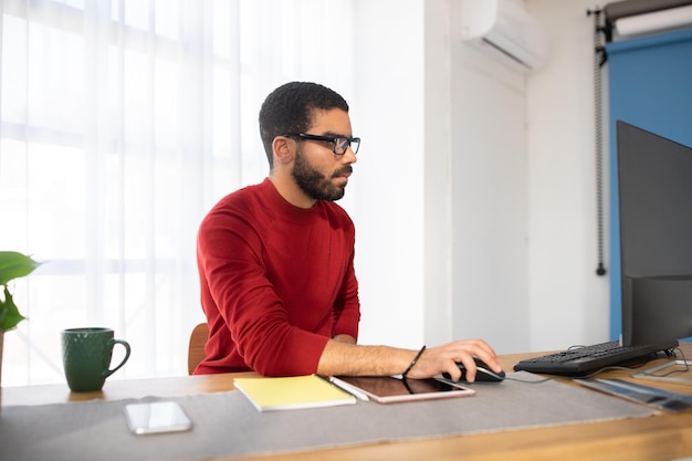 Concentrated young man graphic designer sitting at desk at office