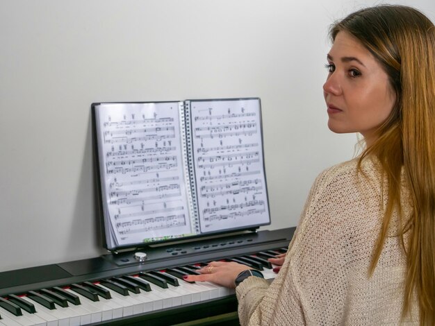 Concentrated young student playing piano and music sheet on the background